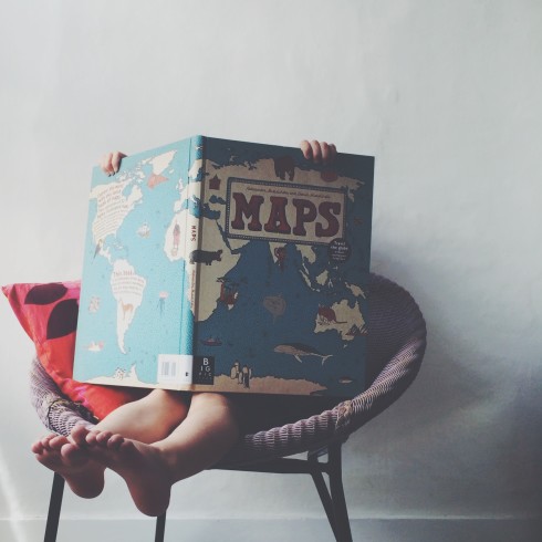 a child holding big book of maps