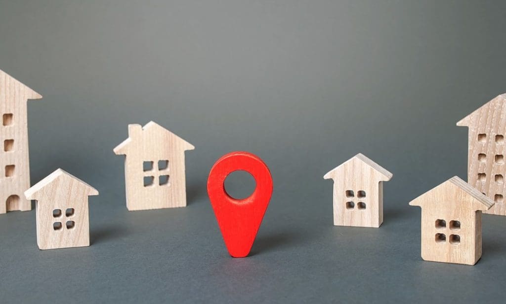 model wooden houses and buildings surrounding a red location icon