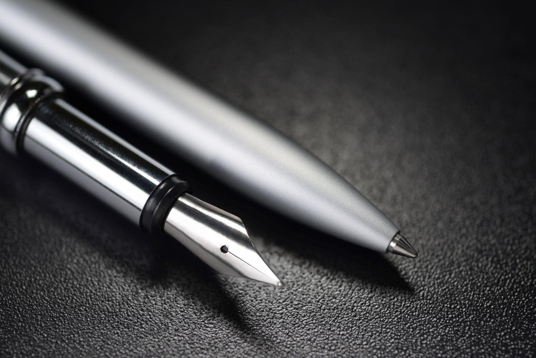 silver ballpoint and fountain pen laying side by side