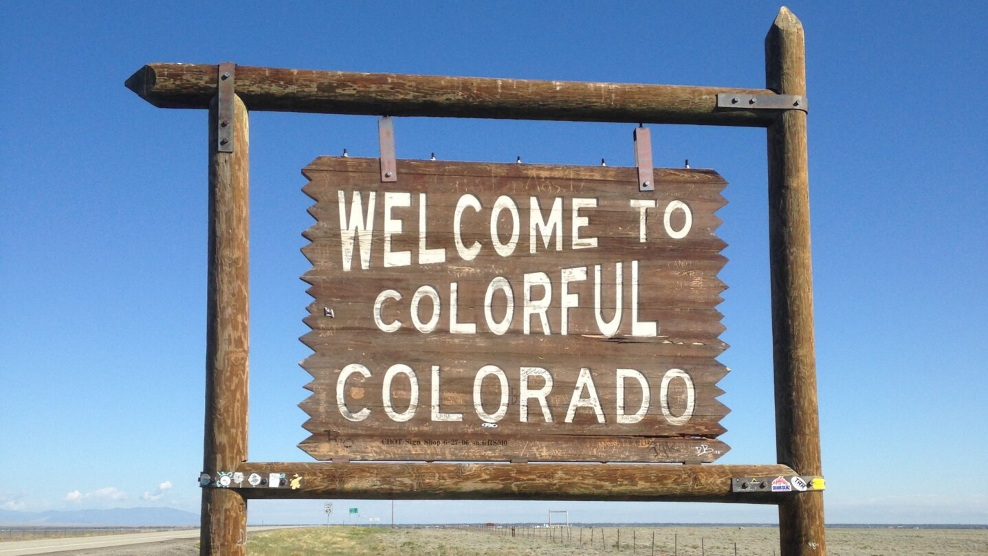 A wooden sign that says Welcome to Colorado