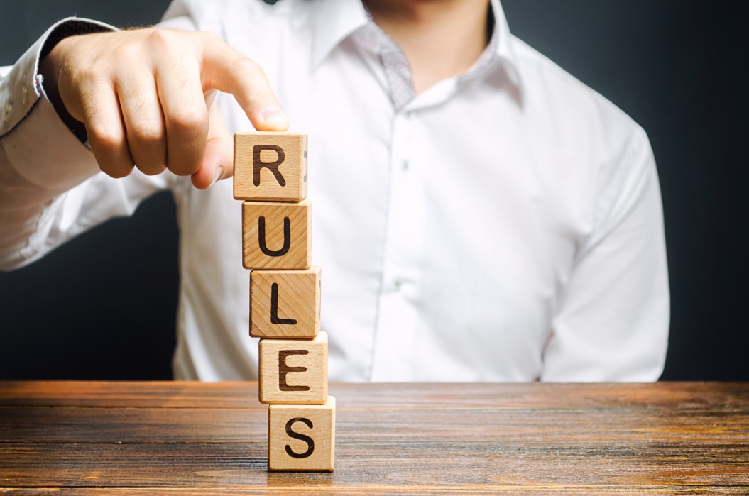 Person balancing wooden blocks that spells out the word "Rules"